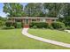 Charming brick home with a well-manicured lawn, beautiful shrubs, and a welcoming walkway to the front door at 388 Talcott Nw Cir, Marietta, GA 30064