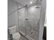 This bathroom features a glass shower with stone tiles, modern fixtures, and gray wood grain flooring at 487 Eastside Dr, Dacula, GA 30019