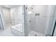 Bright, modern bathroom with tub and glass walk-in shower that features marble tiling and a storage niche at 4541 Meadow Club Dr, Suwanee, GA 30024