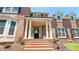 Close up of stately brick home's front entry, featuring columns and landscaped garden at 4541 Meadow Club Dr, Suwanee, GA 30024
