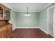 Dining room features hardwood floors, light green walls, white trim, and decorative lighting fixture at 9507 Greens Mill Ct, Loganville, GA 30052