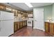 Traditional style kitchen featuring wooden cabinets, white appliances, and hardwood flooring at 9507 Greens Mill Ct, Loganville, GA 30052
