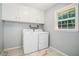 Bright laundry room with window and tile flooring, includes washer, dryer and cabinet storage at 1663 Pounds Sw Rd, Stone Mountain, GA 30087