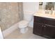 Modern bathroom featuring a dark vanity, patterned shower curtain and tiled floors at 6570 Canyon Cv, Cumming, GA 30028