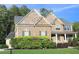 Charming two-story home with a brick and stone facade, well-manicured lawn and mature landscaping at 6570 Canyon Cv, Cumming, GA 30028