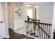 Hallway with hardwood floors, wrought iron stairway, and decorative clock, highlighting a stylish interior design at 6570 Canyon Cv, Cumming, GA 30028