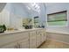 A bathroom with dual sinks, a large mirror, a bathtub and separate shower with natural light from a window at 134 Waterloch Ct, Lawrenceville, GA 30043