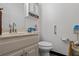 A half bathroom with white vanity and toilet as well as a shelf for extra storage and towel rack at 134 Waterloch Ct, Lawrenceville, GA 30043