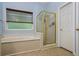 A bathroom with a bathtub, separate shower and a window for natural light and ventilation at 134 Waterloch Ct, Lawrenceville, GA 30043