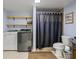 Bathroom with wooden shelves, gray walls, washer and dryer next to stand up shower at 134 Waterloch Ct, Lawrenceville, GA 30043