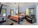 Main bedroom with a four poster bed, an armchair, multiple windows and a ceiling fan with lighting at 134 Waterloch Ct, Lawrenceville, GA 30043