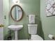 Stylish powder room featuring a pedestal sink, decorative mirror, and fixtures against green painted walls at 1772 Benningfield Sw Dr, Marietta, GA 30064