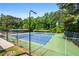 Outdoor tennis court with a blue and green surface, surrounded by fencing and lush trees at 1772 Benningfield Sw Dr, Marietta, GA 30064