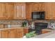 Close-up of updated kitchen features natural wood cabinets, modern appliances, and stone tile backsplash at 6610 Major Dr, Cumming, GA 30040