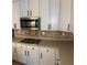 Stylish kitchen boasts white cabinetry, a stainless steel microwave, and diamond patterned backsplash at 753 Hayes Ct, Atlanta, GA 30349