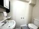 Compact bathroom featuring a sink, mirror, and a toilet with neutral-colored walls at 942 Batesville Rd, Canton, GA 30115