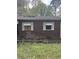 Image of the exterior brick wall, roof damage, with overgrown lawn and boarded window at 2625 Baker Nw Rd, Atlanta, GA 30318