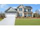 Inviting two-story home features a brick and siding exterior with a two-car garage and a well-manicured front lawn at 5350 Hyde Rd, Cumming, GA 30040