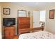 Comfortable bedroom showcasing a wooden dresser with mirror, large TV, and a cozy bed at 7435 Woodruff Way, Stone Mountain, GA 30087