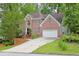 Classic brick home with arched window, lush landscaping, and a wide driveway leading to a two-car garage at 7435 Woodruff Way, Stone Mountain, GA 30087