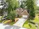 Stately brick home surrounded by mature trees, offering a spacious driveway and attached two-car garage at 7435 Woodruff Way, Stone Mountain, GA 30087