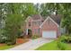 Beautiful brick residence featuring mature trees, lush greenery, and a convenient two-car attached garage at 7435 Woodruff Way, Stone Mountain, GA 30087
