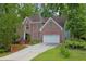Charming two-story brick home with well-manicured lawn, mature trees, and attached two-car garage at 7435 Woodruff Way, Stone Mountain, GA 30087