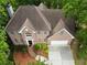 Aerial view showcasing the home's brick facade, two-car garage, driveway, and landscaped front yard at 7435 Woodruff Way, Stone Mountain, GA 30087