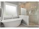 Elegant bathroom featuring a soaking tub, a glass-enclosed shower, and a window for natural light at 1104 Victoria Ne St, Brookhaven, GA 30319