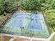 An aerial view shows community tennis courts with a green and blue surface and surrounding trees at 6054 China Rose Ln, Duluth, GA 30097