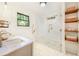 Bright bathroom features a glass shower with herringbone tiling, marble counters, and wood shelving with basket storage at 1231 Mansfield Ne Ave, Atlanta, GA 30307