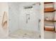Close up of walk-in shower showcasing herringbone tile, river rock flooring, built-in niche, and wooden storage shelves at 1231 Mansfield Ne Ave, Atlanta, GA 30307