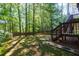 Lush backyard with mature trees, green grass, wooden deck, and a charming stone pathway at 2015 Towne Lake W Hls, Woodstock, GA 30189