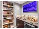 Basement bar area with shelves, glassware and sports memorabilia displayed near a large screen television at 2015 Towne Lake W Hls, Woodstock, GA 30189