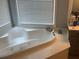 Bright bathroom featuring a large tub under a window with blinds at 2015 Towne Lake W Hls, Woodstock, GA 30189