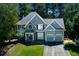 Stunning two-story home featuring stone and gray siding, a two-car garage, and lush landscaping at 2015 Towne Lake W Hls, Woodstock, GA 30189