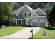 Charming two-story home featuring a well-manicured lawn, gray siding, a stone facade, and a three car garage at 2015 Towne Lake W Hls, Woodstock, GA 30189