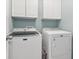 Laundry room has white cabinets above a front loading washer and dryer at 2015 Towne Lake W Hls, Woodstock, GA 30189