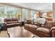 Comfortable living room featuring large windows, leather sofas, and open kitchen view at 2015 Towne Lake W Hls, Woodstock, GA 30189