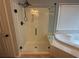 A modern glass shower with black hardware and a built-in seat adjacent to the soaking tub at 2015 Towne Lake W Hls, Woodstock, GA 30189