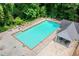 A refreshing in-ground pool surrounded by lounge chairs, umbrellas and trees provides a relaxing outdoor space at 2605 Woodland Hills Dr, Cumming, GA 30040