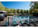 Community pool with lounge chairs surrounded by a black metal fence and mature trees at 3147 Buford Ne Hwy # 8, Brookhaven, GA 30329