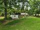 Green backyard area with various trees and a fenced-in structure at 350 Lakeview Dr, Brooks, GA 30205