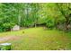 Spacious, green backyard with mature trees and foliage, with a storage shed at the rear of the property at 5293 Sandy Shoals Ln, Stone Mountain, GA 30087