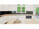 Bright kitchen featuring white cabinets, black backsplash, and an island with a stainless steel sink at 765 Brooks Cir, Stone Mountain, GA 30087