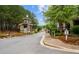 Stone entrance to the community with lush landscaping, signage indicating the sales center, and a gated entry at 114 Village Green Ave, Woodstock, GA 30189