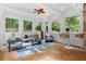 Light filled sunroom boasting wooded views from many windows, tile floors and comfortable seating arrangement at 3905 Merriweather Woods, Johns Creek, GA 30022