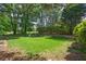 Well-kept backyard with green grass and mature trees and shrubs, surrounded by a rock wall and trees at 320 Ironhill Trce, Woodstock, GA 30189