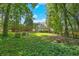 Lush backyard with mature trees offering privacy, showcasing the deck and upper level of the home at 320 Ironhill Trce, Woodstock, GA 30189