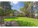 Beautiful backyard featuring a lush lawn, mature trees, and a stone patio with seating, perfect for outdoor enjoyment at 320 Ironhill Trce, Woodstock, GA 30189